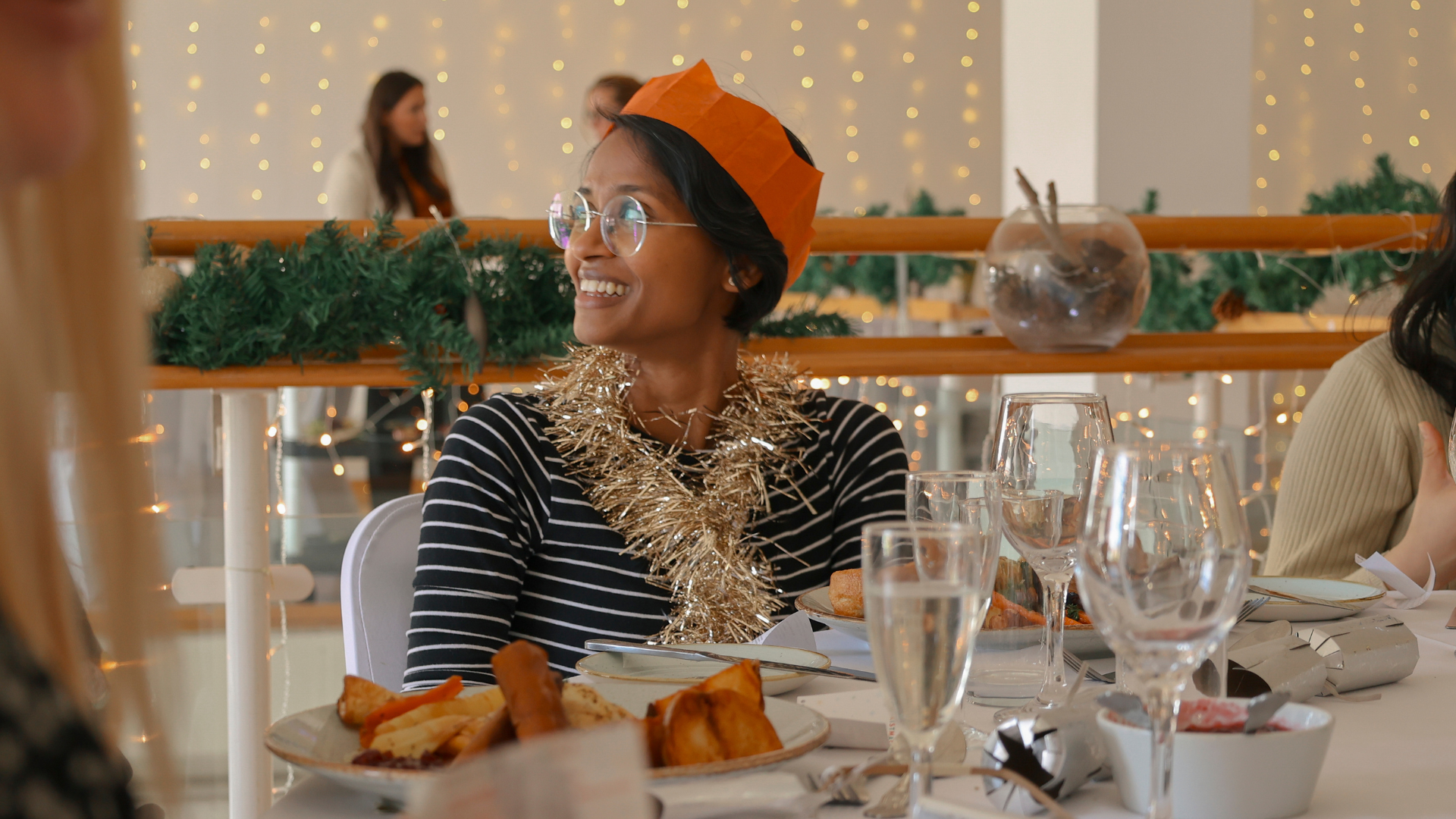 Guest smiles wearing Christmas decs and eating roast dinner