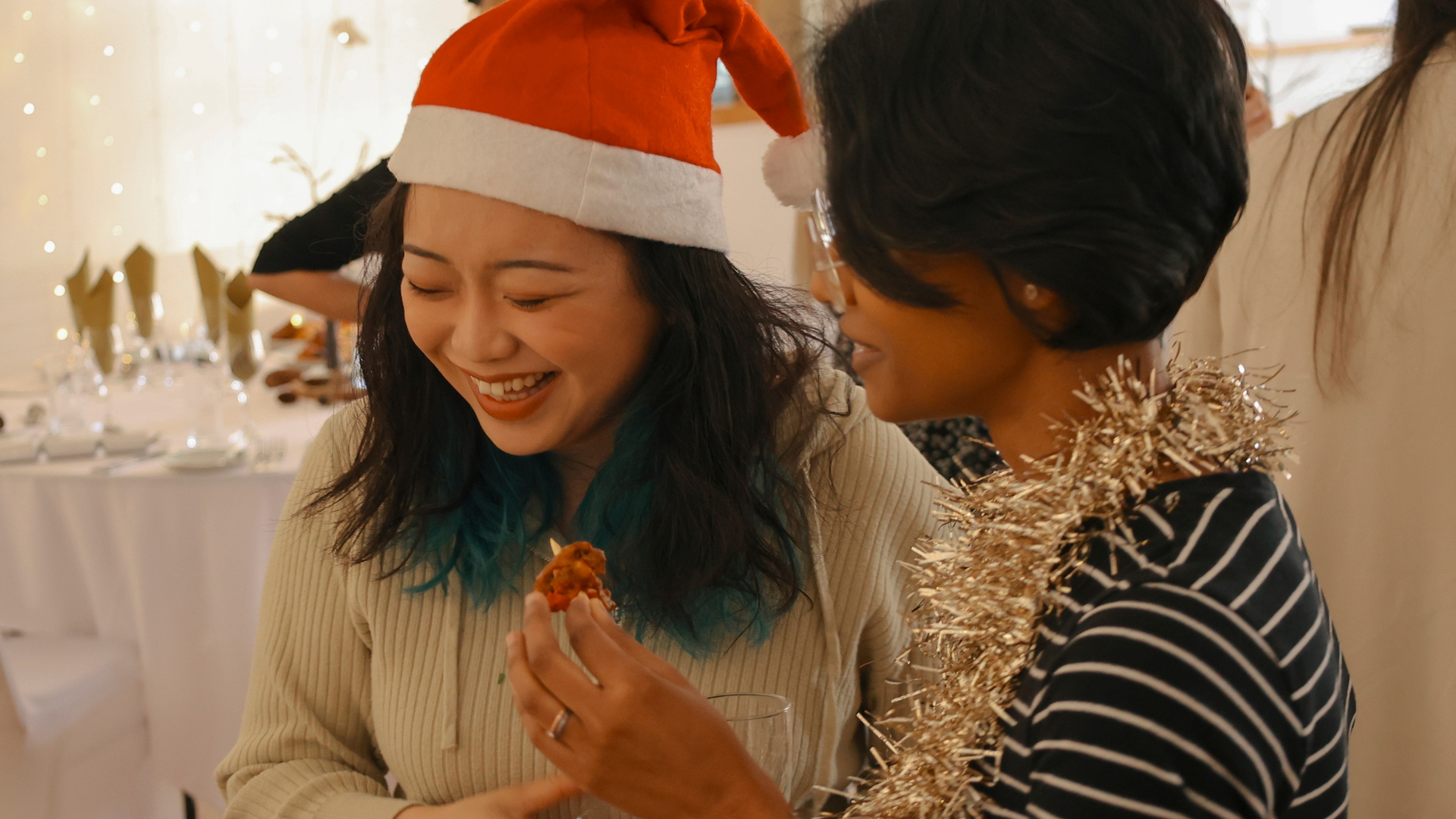 Two women chat and laugh at a Christmas party