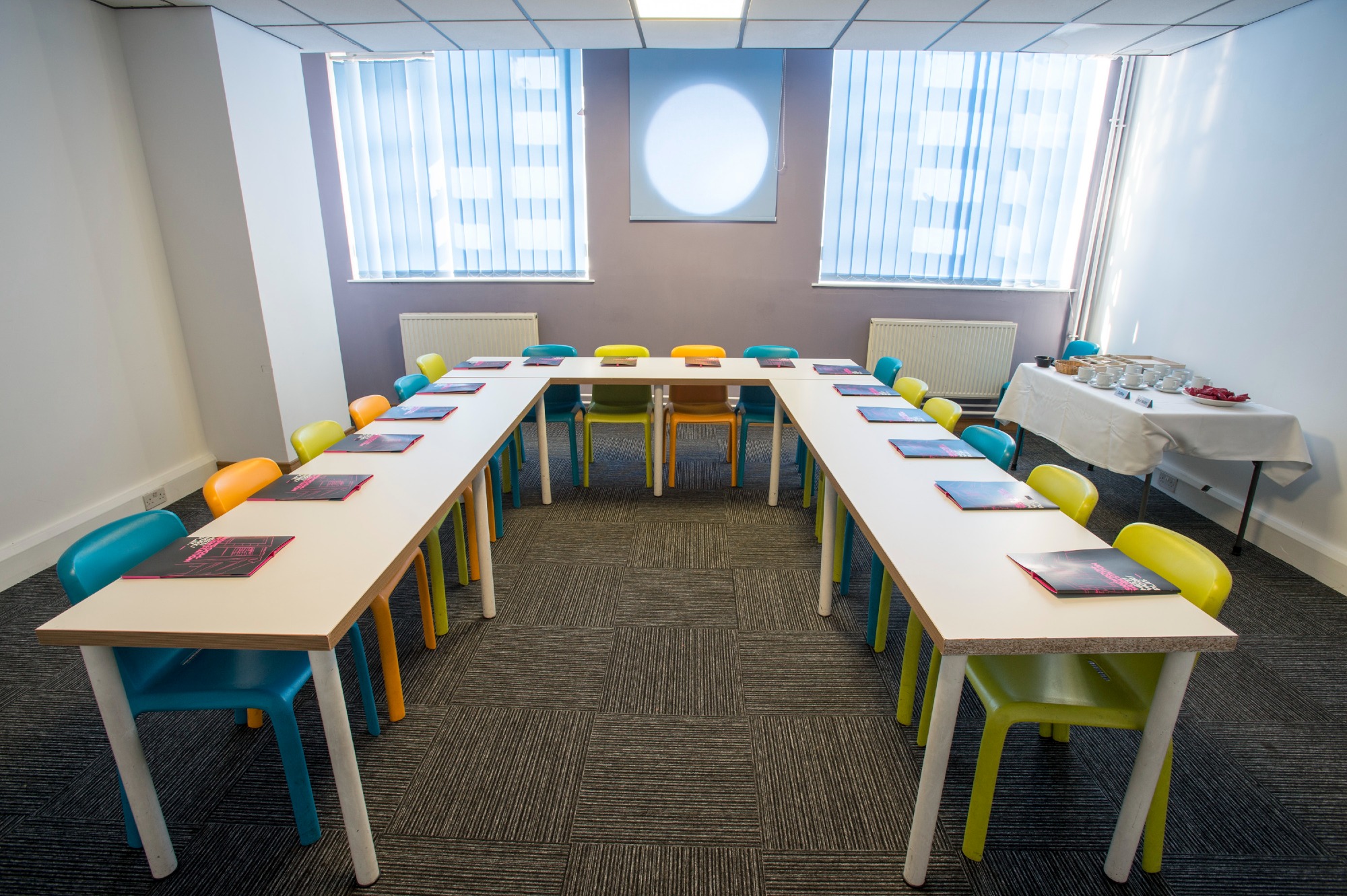 Conference room 2 with colourful chairs and light coming through the windows.