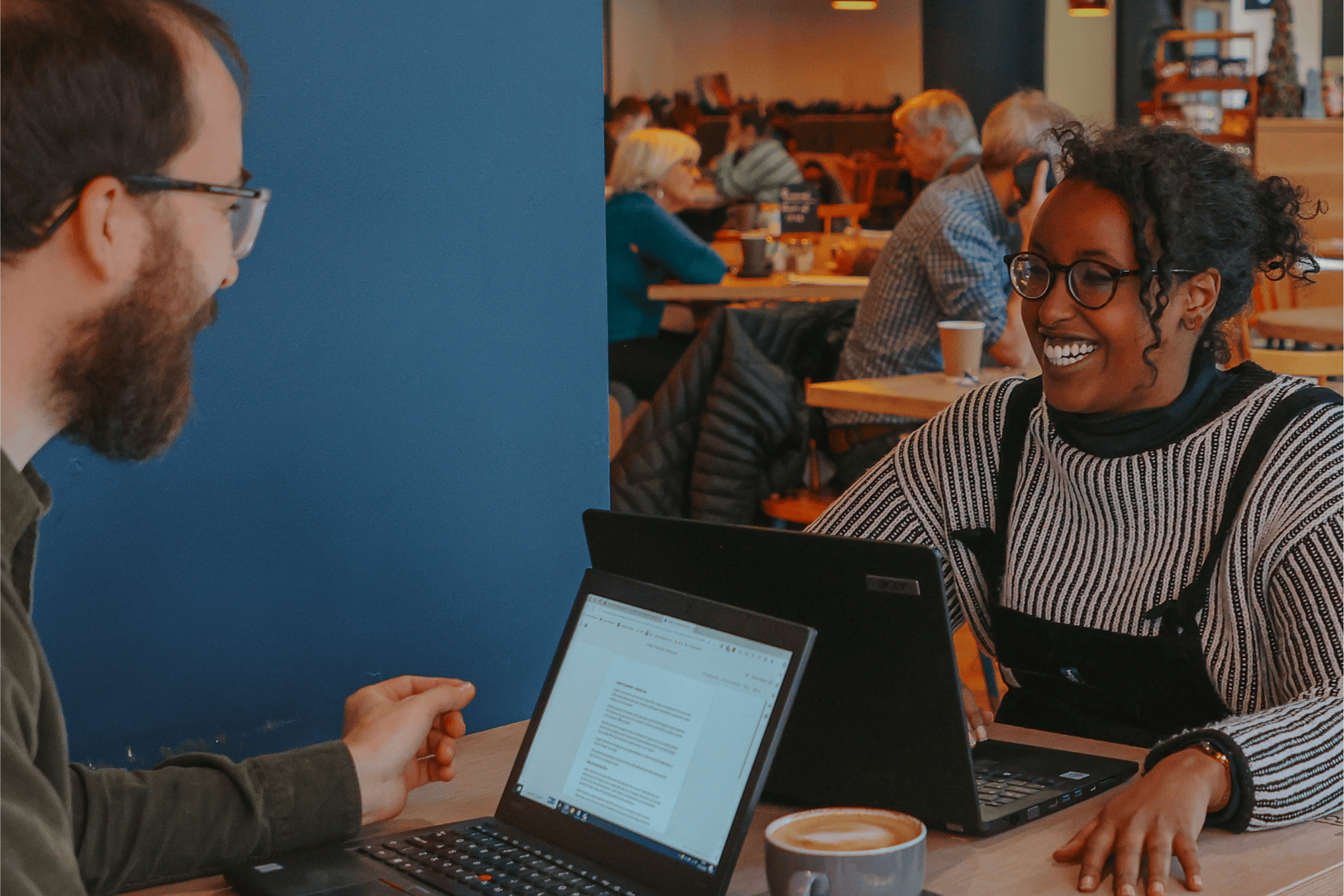Two people sit smiling at eachother and working in Showroom's Cafe Bar.