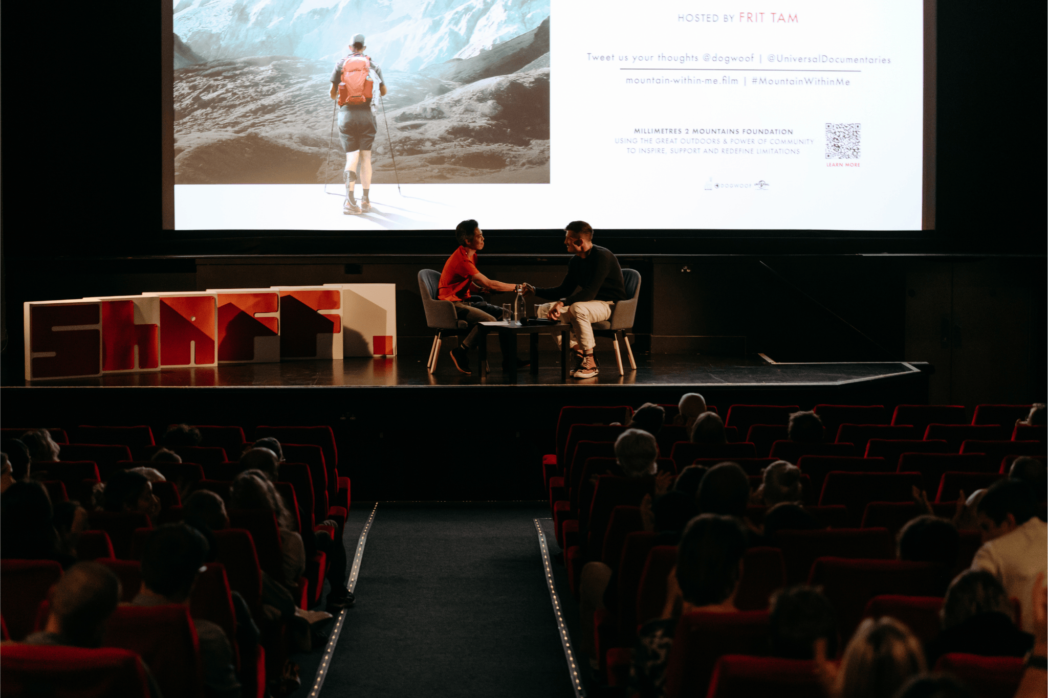 Two people shake hands on stage at Sheffield Adventure Film Festival